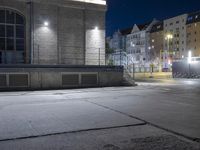 a sidewalk in the city at night time with an out of focus building in the background