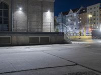 a sidewalk in the city at night time with an out of focus building in the background