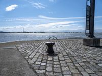 an old cobblestone walkway along a body of water and with a dock in the background