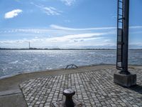 an old cobblestone walkway along a body of water and with a dock in the background