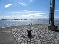 an old cobblestone walkway along a body of water and with a dock in the background