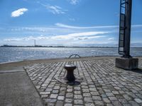 an old cobblestone walkway along a body of water and with a dock in the background