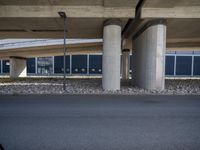 a person is riding down a street in front of a building with concrete columns and a black sky scrape