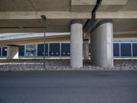 a person is riding down a street in front of a building with concrete columns and a black sky scrape