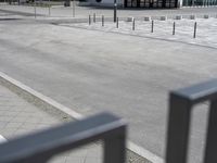 a skateboarder is riding along a sidewalk outside of an arena with others sitting on the benches