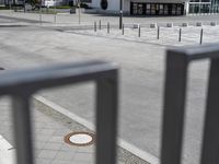 a skateboarder is riding along a sidewalk outside of an arena with others sitting on the benches