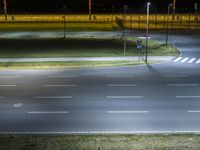 an empty street lit up at night at the intersection of two roads with a traffic light in