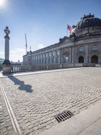 a courtyard outside of a museum with a manhole at the base of it and some spires on the building