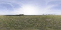 an 360 view of the fields of grass, clouds and buildings in a sunny day