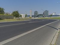 the street with two cars is empty in front of some city buildings by water in a sunny day