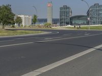 the street with two cars is empty in front of some city buildings by water in a sunny day