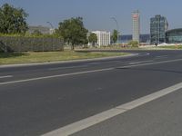 the street with two cars is empty in front of some city buildings by water in a sunny day