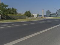 the street with two cars is empty in front of some city buildings by water in a sunny day