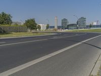 the street with two cars is empty in front of some city buildings by water in a sunny day