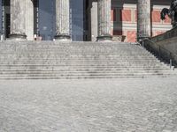 some stairs up to a building with statues on it and some large columns behind it