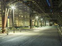 an empty city street under a bridge at night, with street lights on at either end