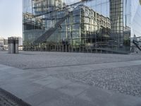 a modern glass building is reflected in the mirror windows of it's outside area