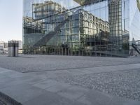 a modern glass building is reflected in the mirror windows of it's outside area