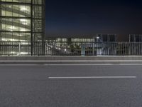 a view of city buildings in the background at night with an empty roadway on the left side of the street