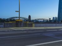 a cyclist on the sidewalk of a bridge next to some tall buildings and a bridge