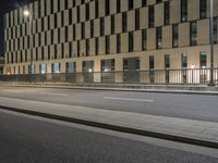 the building next to the street is lit up with lights and traffic signs as the person walks