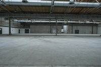 an empty building with pipes and large ceilings over it a person is walking into the open door