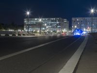 large building on the street with lights in front and other buildings nearby at night with no one moving