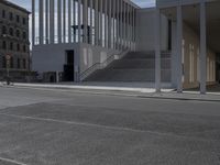 a person on a skate board riding down the road with stairs in the background and stairs leading to large white buildings