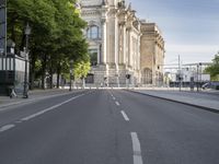 a road that has a street light on it at the end of it and a building with an arch behind it