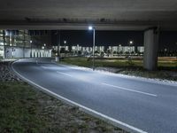 a road with some lights near a highway side at night time by a construction structure