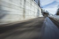 a car driving down the road by some snow covered trees and wall wall as seen from below