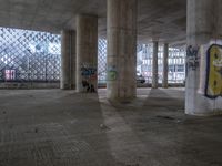 a large building with concrete columns and graffiti on the walls and floor inside and under