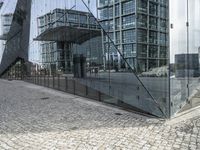 the building is built around a glass wall on the street curb with a reflection in the glass