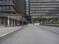 the buildings in this photo are glassy and are grey with metal accents and some plants