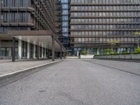 the buildings in this photo are glassy and are grey with metal accents and some plants