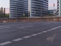 a building in the background is dark and clear with white lines on it and empty road, traffic and street signs