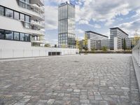 an urban courtyard area with cobblestone and modern buildings in the background by the water