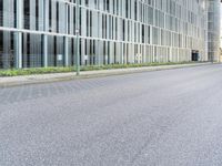 a motorcycle parked on the side of a street in front of a tall building with glass windows