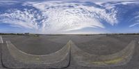 an image of a large empty runway with some clouds in the sky over it and some cones