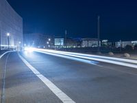 large building on the street with lights in front and other buildings nearby at night with no one moving