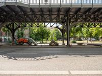 cars are sitting underneath an overpass on the side walk of a street with benches