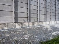 a brick sidewalk with windows next to buildings and trees in the background on a sunny day