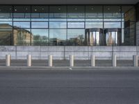 a picture of a building with a glass facade and multiple columns on each side of it
