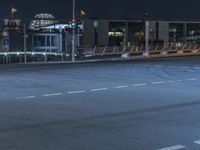 a man riding his skateboard down the street at night time, with the traffic signals above him