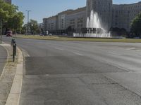 this is a picture of a park with fountains on the street and two people crossing