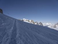 a person skiing down a snowy slope on a sunny day's day near mountains