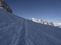 a person skiing down a snowy slope on a sunny day's day near mountains