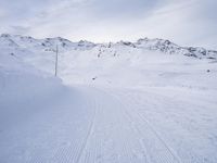 snow covered slope in the middle of a ski area as people ski on it near ski lift