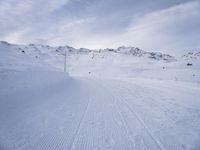 snow covered slope in the middle of a ski area as people ski on it near ski lift