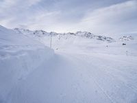 snow covered slope in the middle of a ski area as people ski on it near ski lift